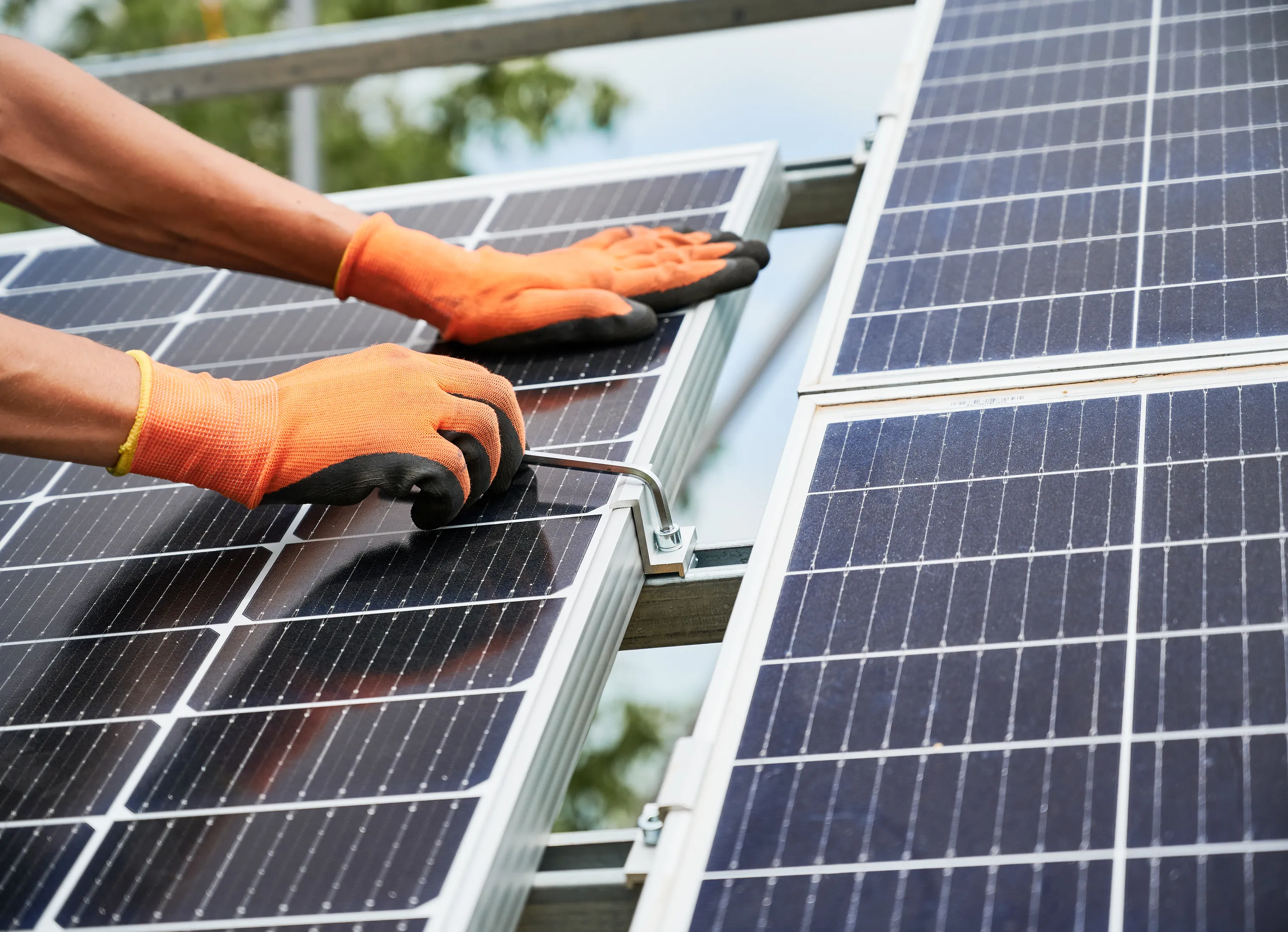 Käsineet kädet asentavat aurinkopaneelia osana energia-asennusta.